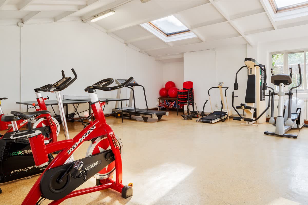 Sala con bicicletas estáticas, cintas de correr y máquina de musculación, iluminada por claraboyas