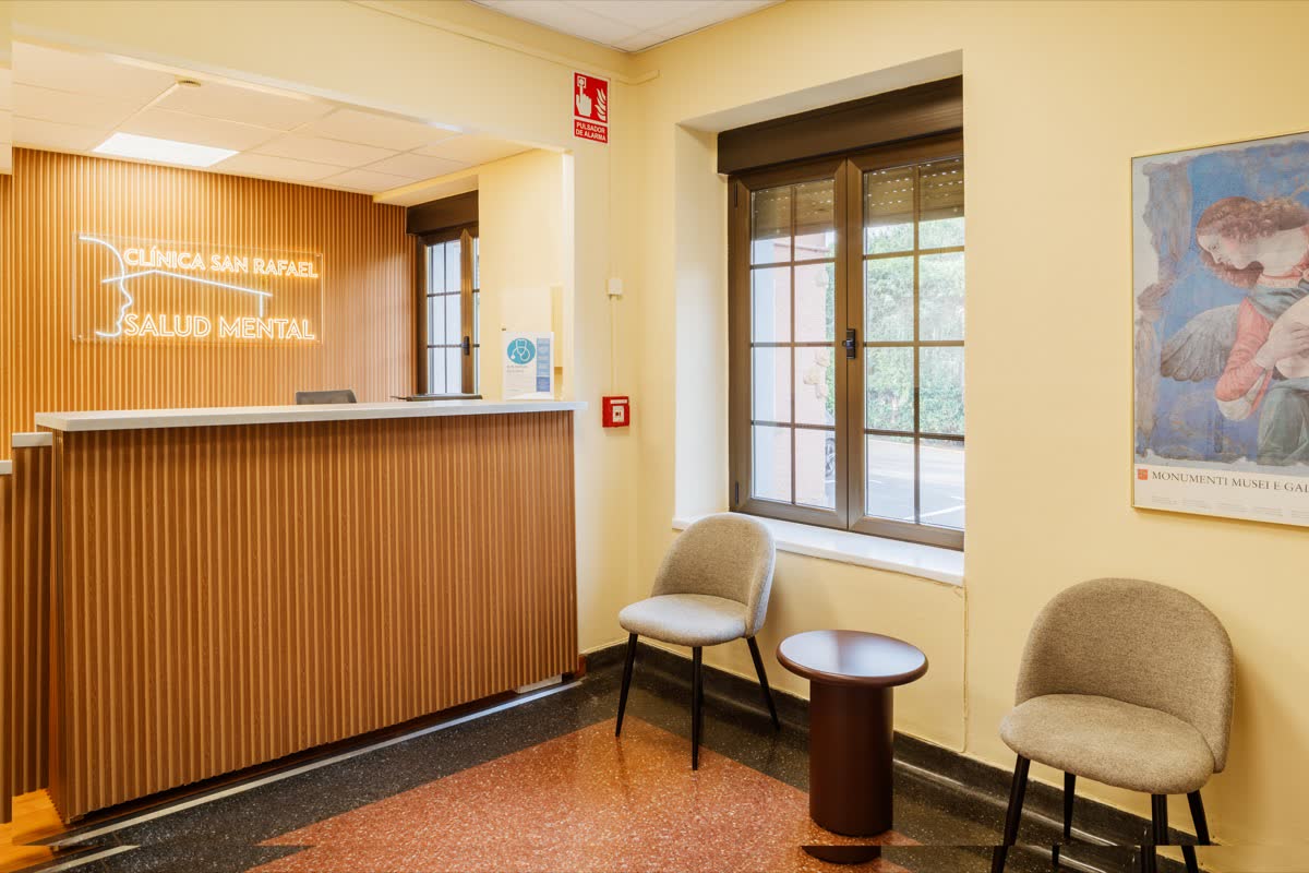 Mostrador de recepción de madera con el rótulo Clínica San Rafael Salud Mental y dos butacas de espera